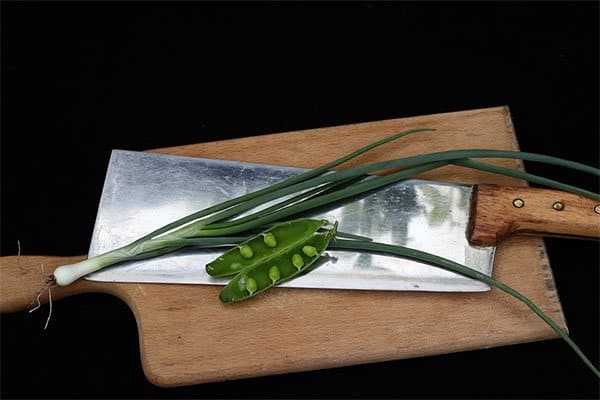 A meat cleaver with green vegetables