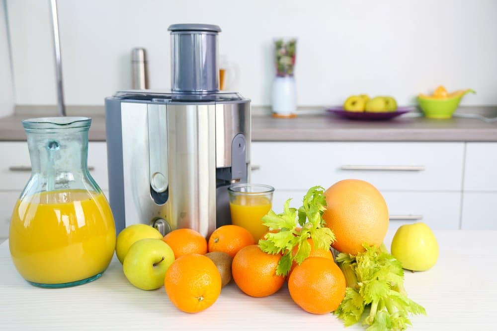 Oranges, Apples and greens next to juicer