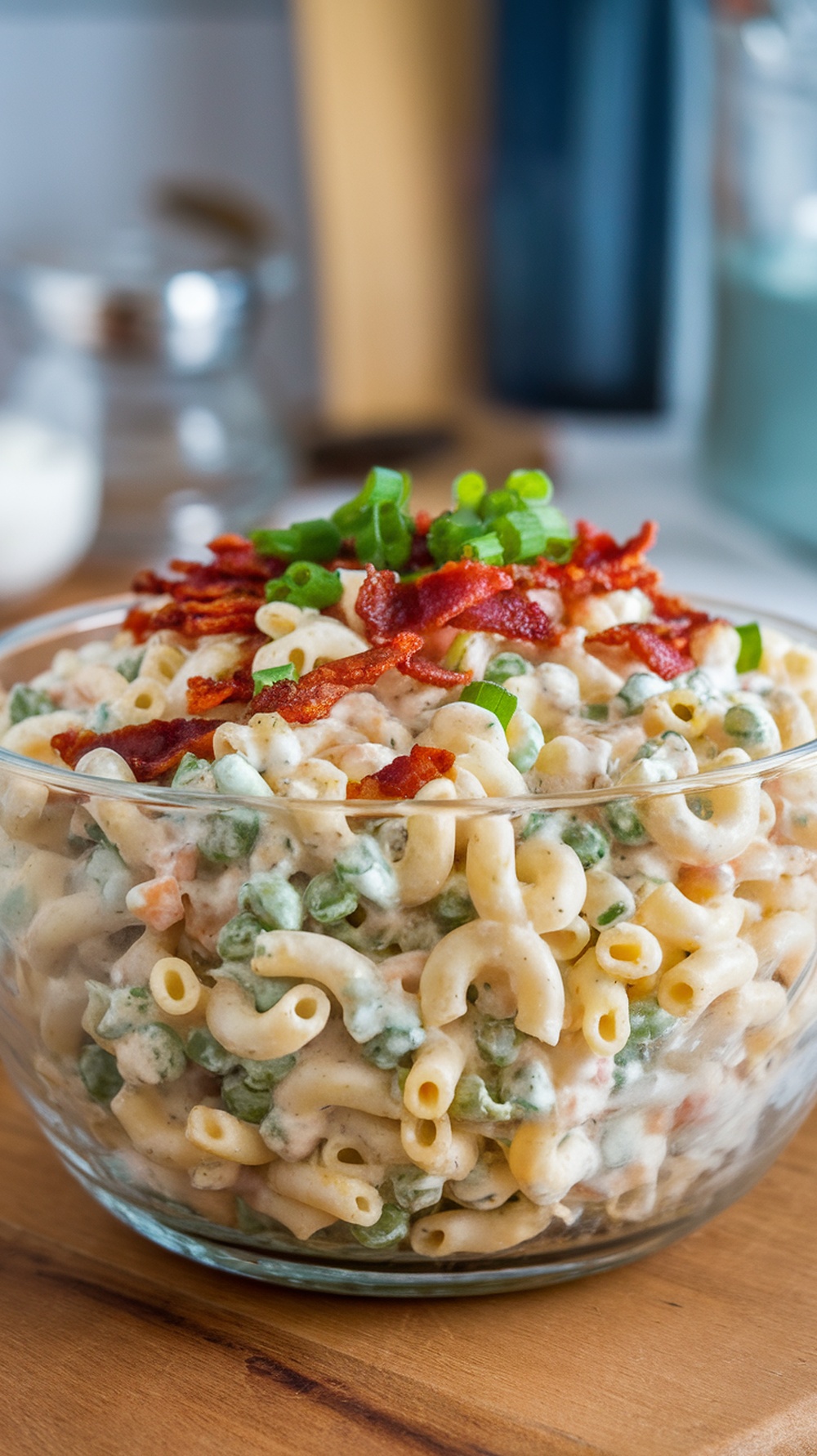 A bowl of savory bacon ranch pasta salad with peas, topped with crumbled bacon and green onions.