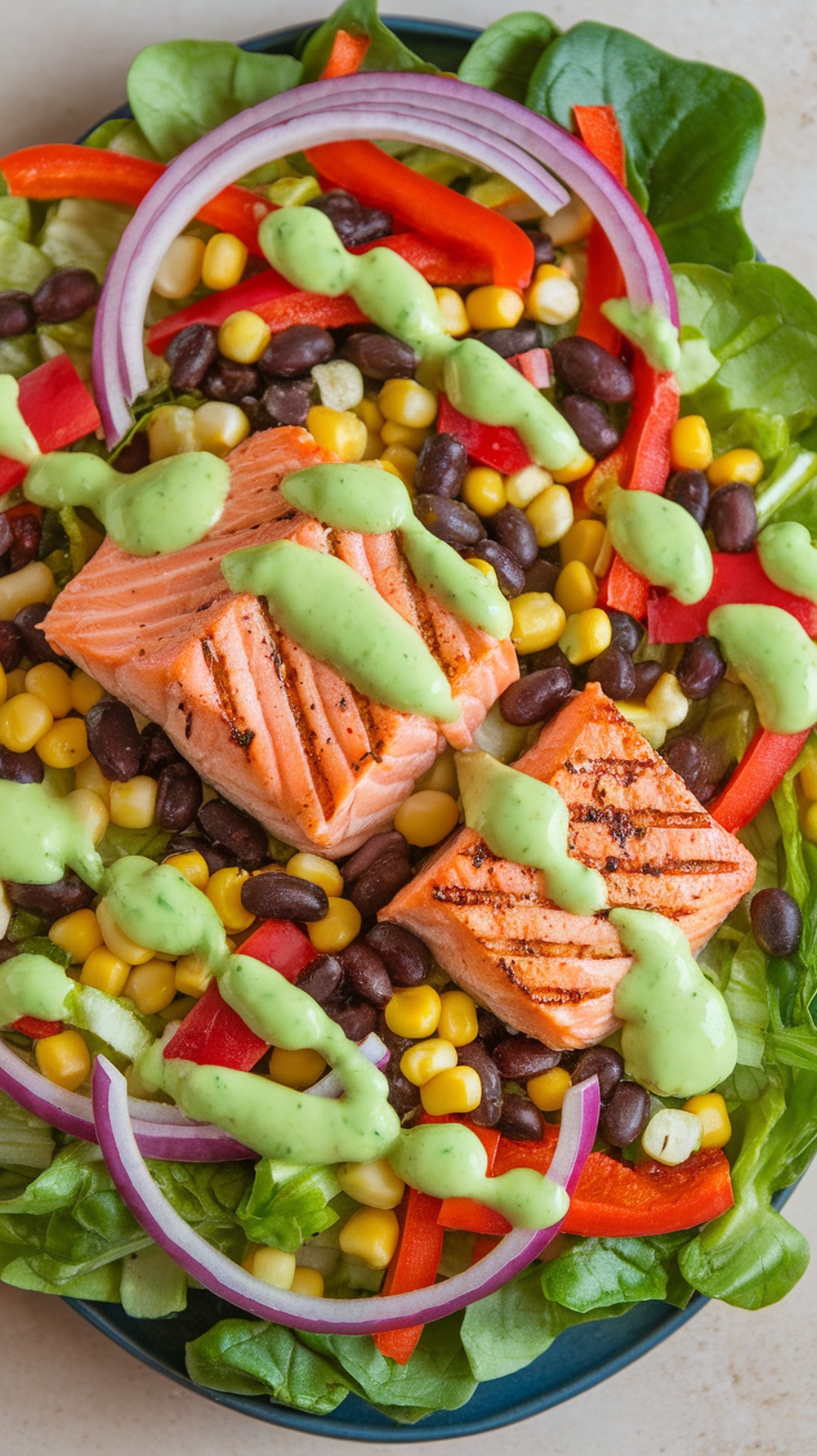 A colorful Southwest Salmon Salad with grilled salmon, mixed greens, black beans, corn, and avocado dressing.
