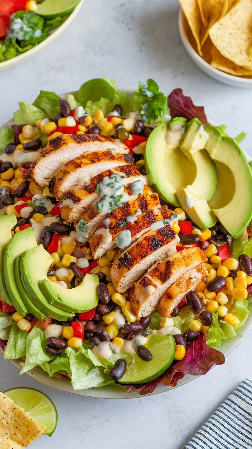 A colorful Spicy Southwest Grilled Chicken Salad with avocado, corn, black beans, and grilled chicken slices.