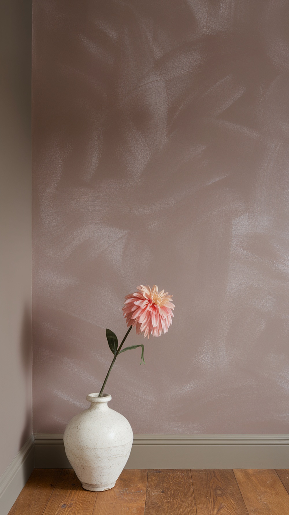 A soft taupe wall painted in Moth Wing by Sherwin Williams, featuring a vase with a pink flower.