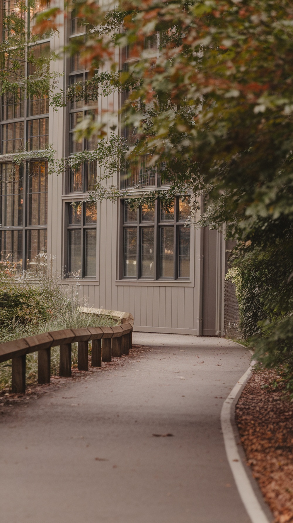 A winding jogging path surrounded by greenery and a beige building.